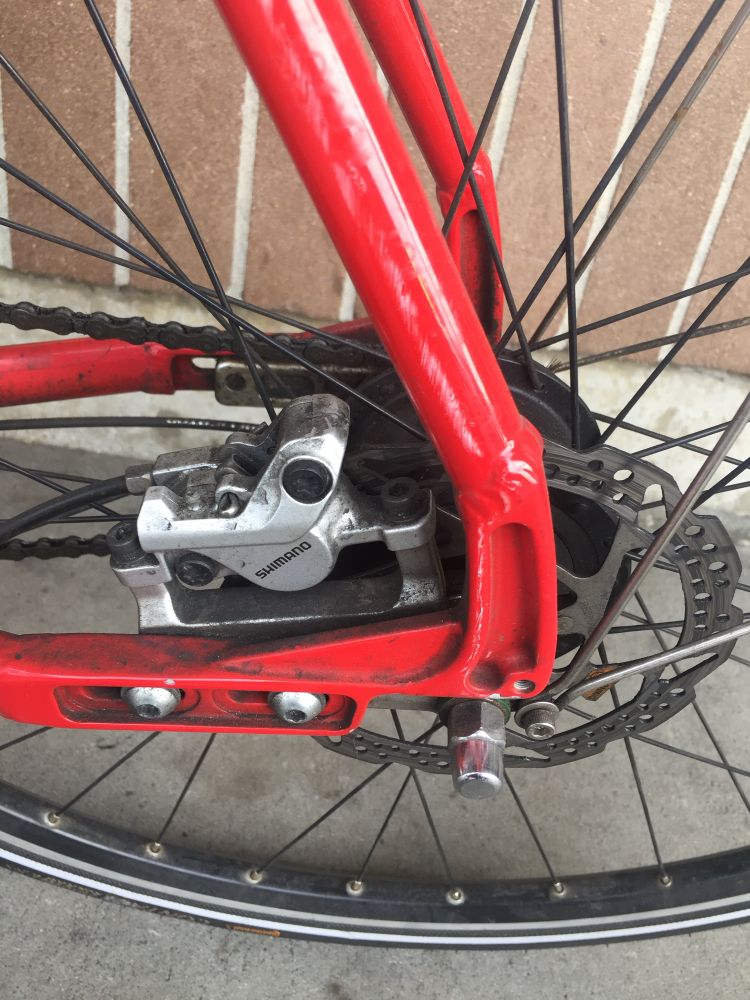 Rear bike hub with disk brakes. Red frame and black rims/spokes. In need of a scrub