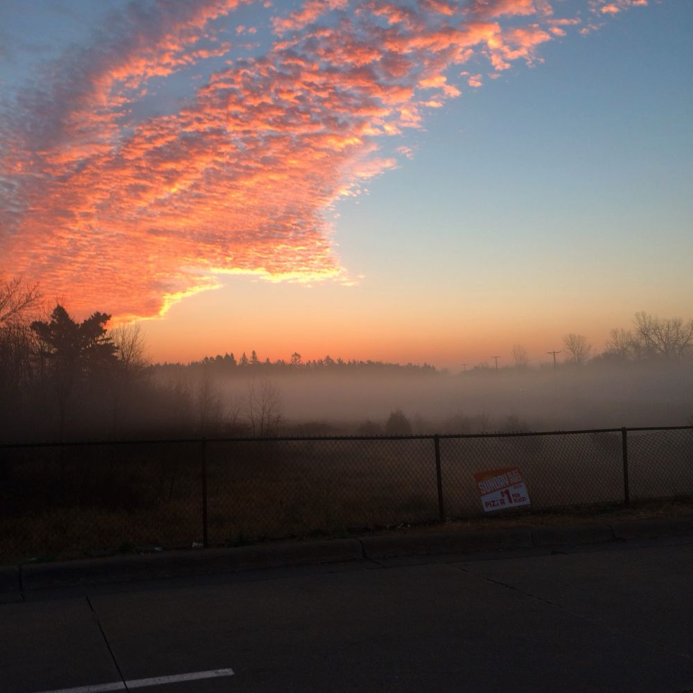 Rose colored clouds over a misty field
