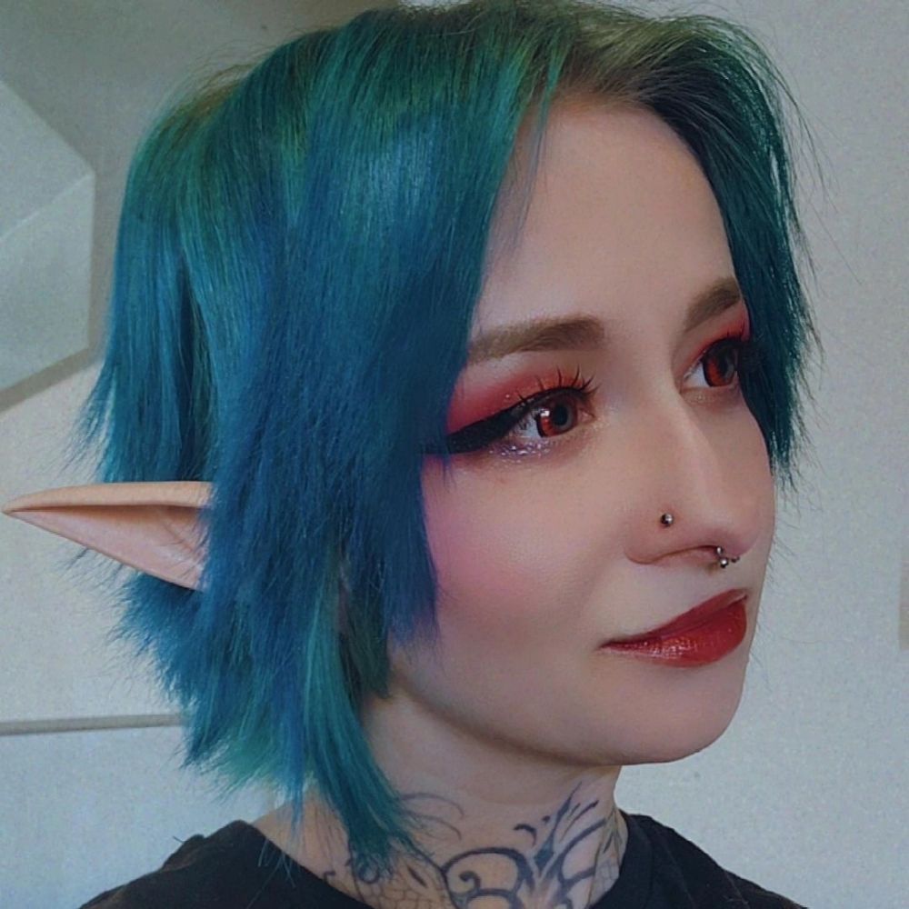 A head shot of Boba with blue hair and wearing Elf ears
