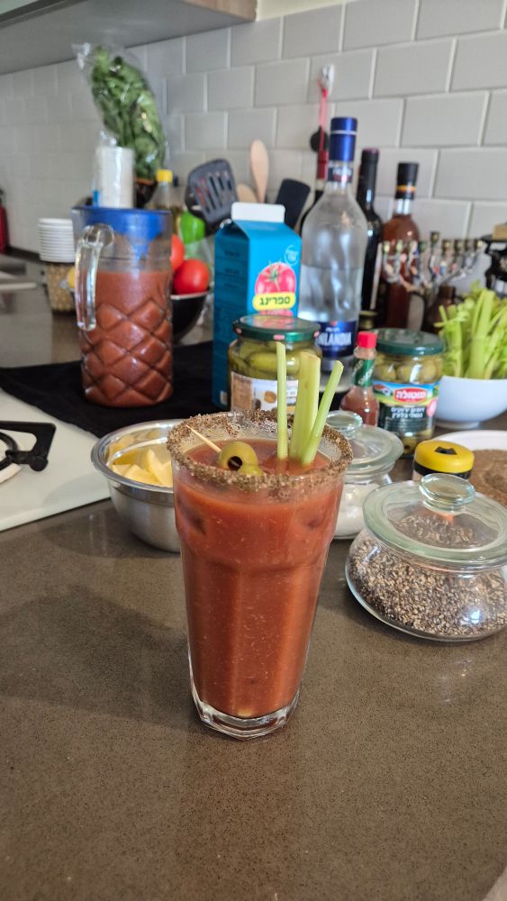 Bloody Mary with homemade mix, additions and garnishes in the background 
