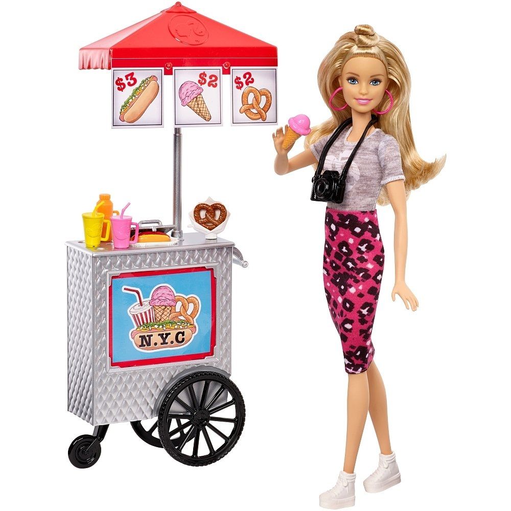 eine Barbie in sommerlicher Kleidung neben einem mobilen Essenswagen, der HotDogs, Eis und Brezeln verkauft