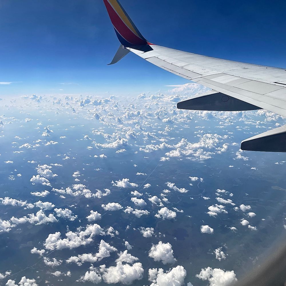 Aircraft wind over blue sky and clouds.