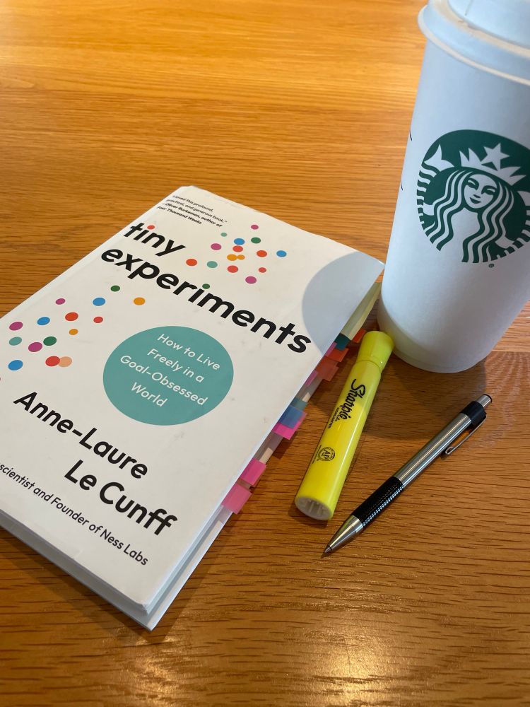 A book, highlighting marker, pen, and coffee cup,