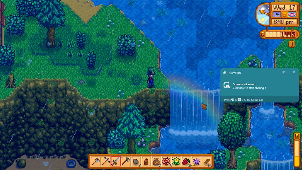 screenshot of a rainy stardew day with a rainbow across the waterfall near the hat mouse. I am wearing a leprechaun hat, having walked across the pot of gold before taking the screenshot