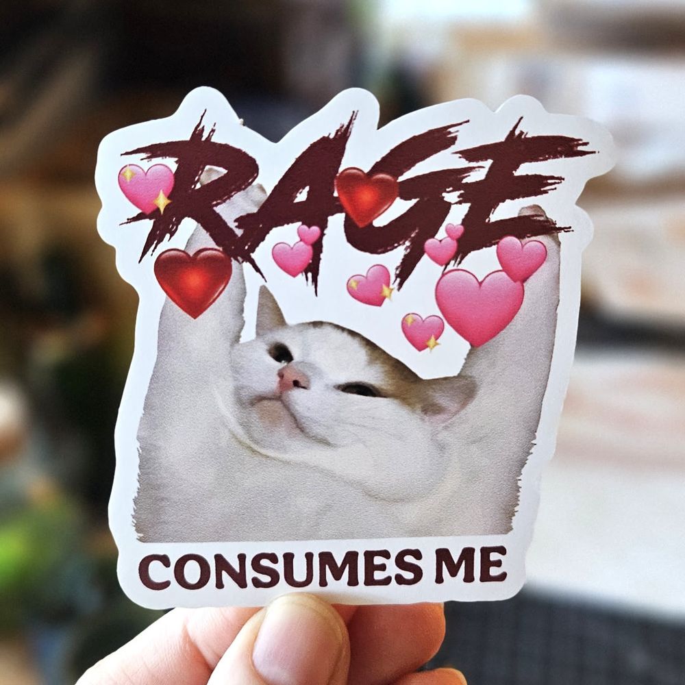A die-cut sticker featuring a chubby white and brown cat with its paws raised, surrounded by floating pink and red heart emojis. Above the cat, the word "RAGE" is written in bold, distressed red lettering, while below it, the phrase "CONSUMES ME" appears in deep red text. The combination of aggressive typography and soft heart emojis creates a humorous contrast, making the design both chaotic and endearing.