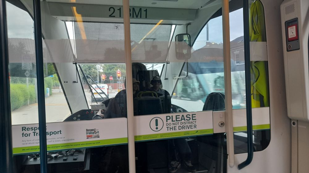 A view from the front of an NET tram showing the glass screen separating the drivers cab. There is a label which reads "Please do not distract the driver!"