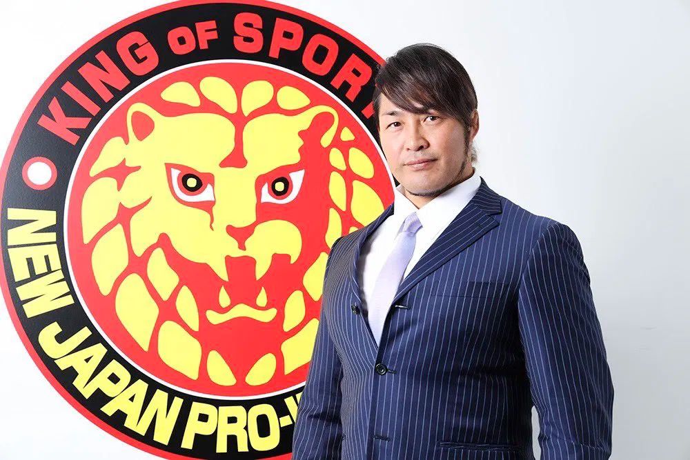 Hiroshi Tanahashi standing in front of the NJPW logo