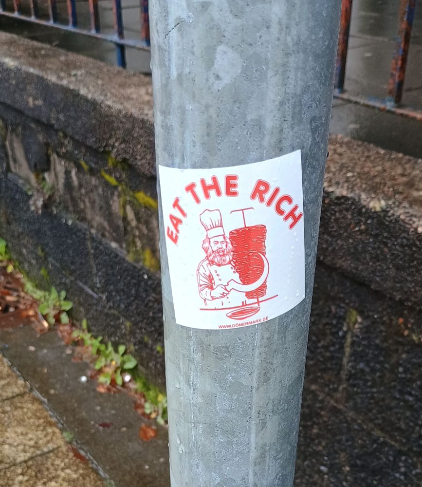 Sticker

The words "eat the rich" over a drawing of Karl Marx holding a sickle next to a meat cone. 