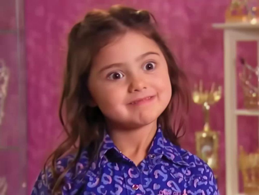 a little girl wearing a leopard print shirt is making a face