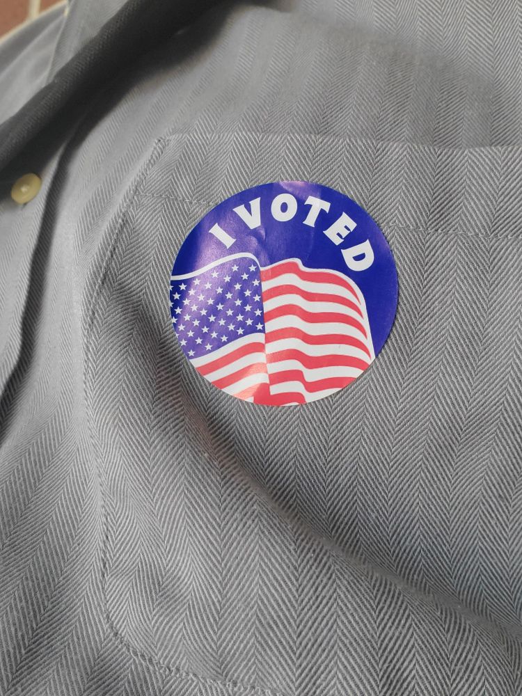 Closeup of a man's shirt with a sticker reading "I voted"