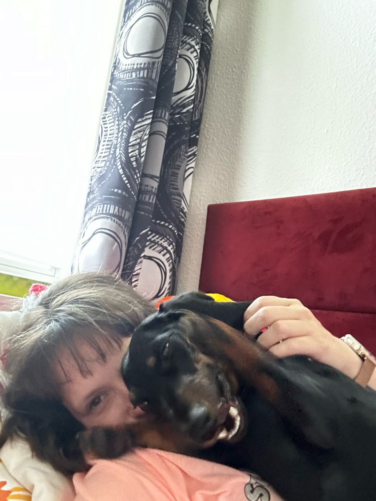 Ein Selfie von mir und einem schwarz braunen Dackel. Sie liegt auf mir und lacht
