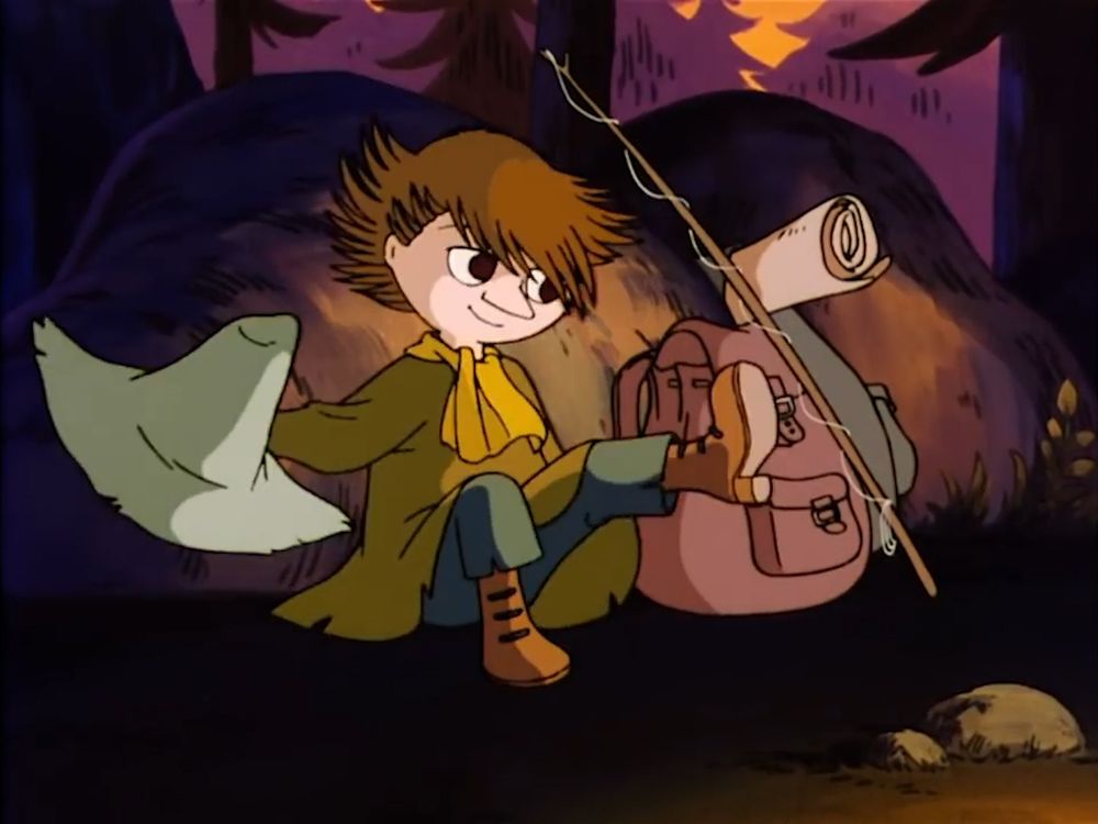 Snufkin sitting down against a big rock, while removing his hat. 