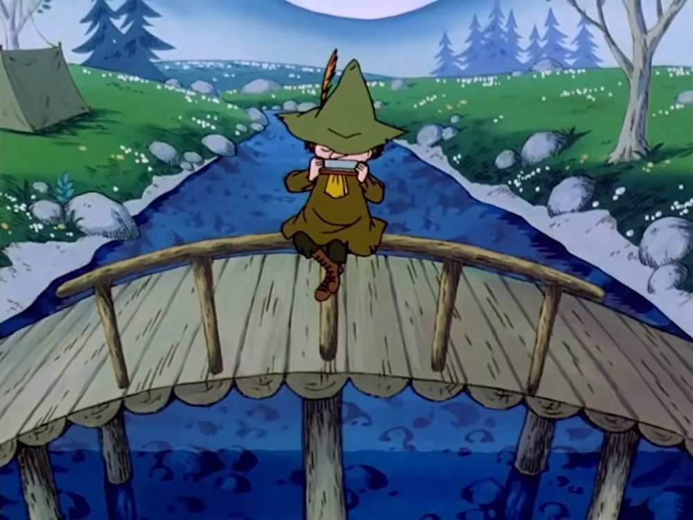 Snufkin playing the harmonica while sitting on the railing of the bridge. 