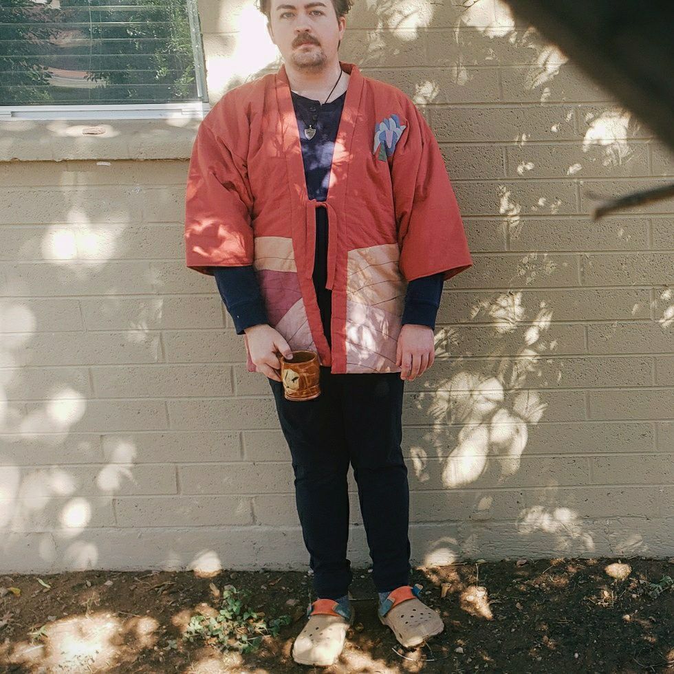 Me in a padded japanese style jacket that's mostly salmon colored. There's an iris flower made with pieces of cloth sewn over the left chest area