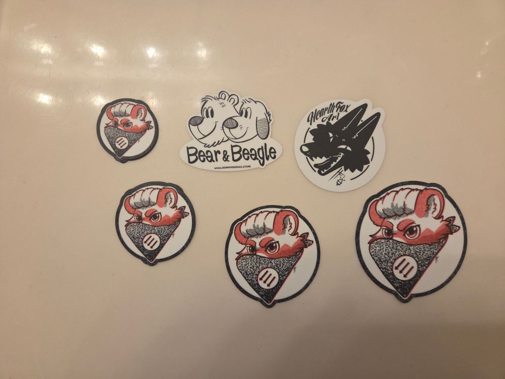 A collection of stickers made by Bear & Beagle with art from HearthFox (with each artist's own logo included as their own stickers)