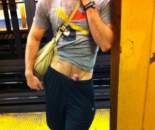 anonymous roman god shaped dude on the subway. tshirt shorts satchel. showing naked band of midriff with his erection pinned facing up and out of his shorts