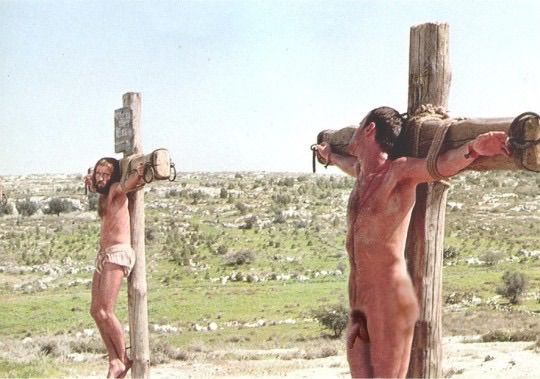two dudes being crucified, the closer one has a rocking bod and free hanging dick