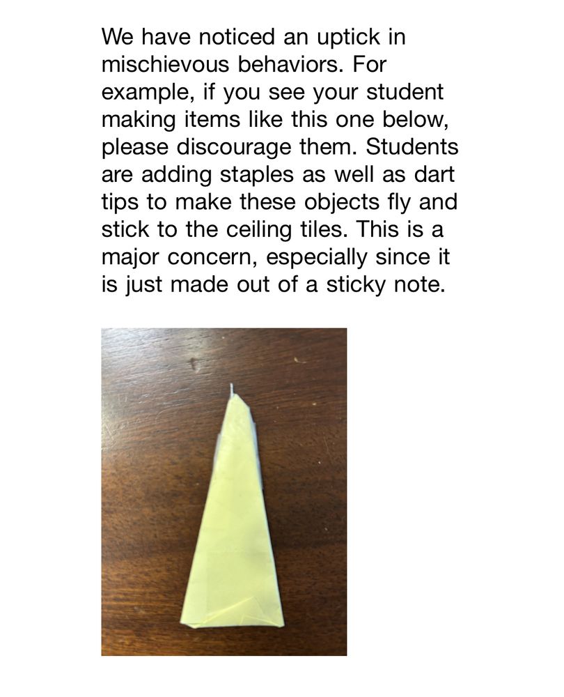 A photo of a yellow sticky note folded into a triangle. A small silver pointy bit is visible sticking out of the top corner of the triangle. Above the photo is the following text: “We have noticed an uptick in mischievous behaviors. For example, if you see your student making items like this one below, please discourage them. Students are adding staples as well as dart tips to make these objects fly and stick to the ceiling tiles. This is a major concern, especially since it is just made out of a sticky note.”
