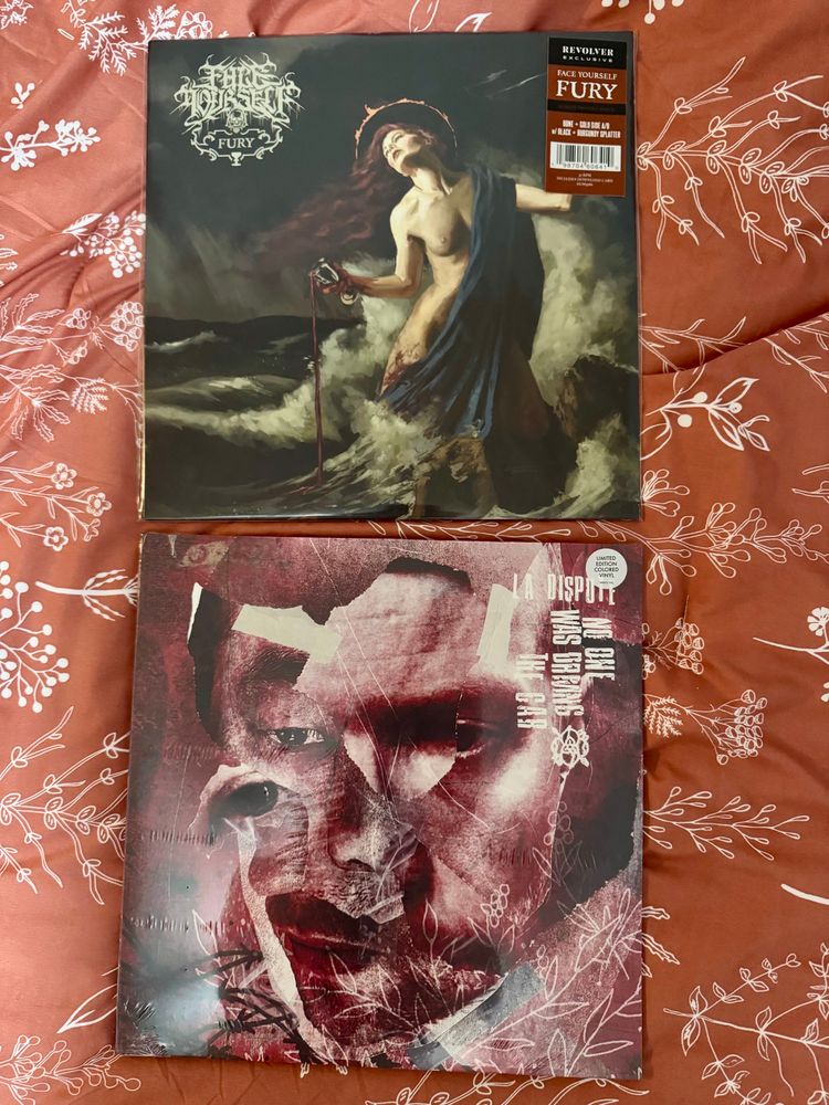 two vinyl records, 

Face Yourself - Fury 
Shows a half covered had naked woman with a cup of blood pouring out into the dark ocean color she’s in. Storm clouds in the distance while she has one breast free and the other half covered by a blue fabric 

La Dispute - No One Is Driving The Car 
Shows red and white colors in different shades with a drawing a person’s face staring into the abyss. the thousand eye stare, with fragments of the artwork moved around to give affect. 