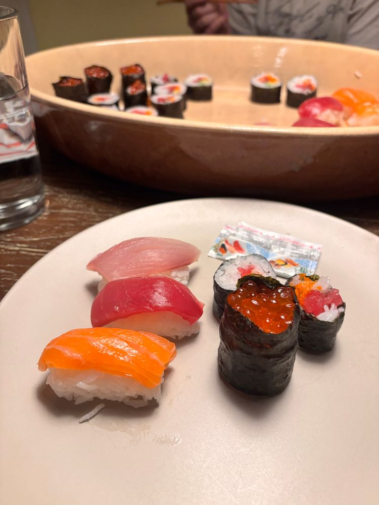 A plate of assorted sushi with a serving tray in the background 