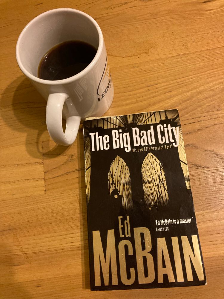 The Big Bad City by Ed McBain in a UK paperback & a Leinster Rugby mug full of black coffee. 