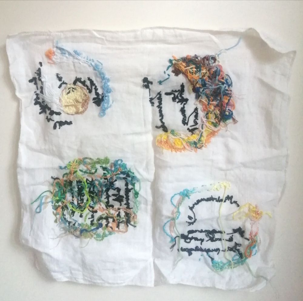 un mouchoir brodé déplié, mais photographié sur son envers, ce qui fait que les broderies ne sont pas lisibles, ni figuratives