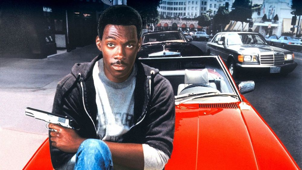 Eddie Murphy sitting on the hood of a red convertible (movie poster for Beverley Hills Cop).