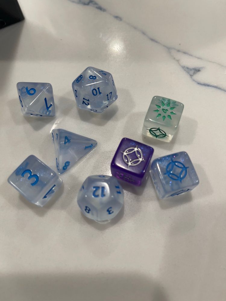 The Dice from stormlight, which are mostly translucent blue, with one light green and one purple.