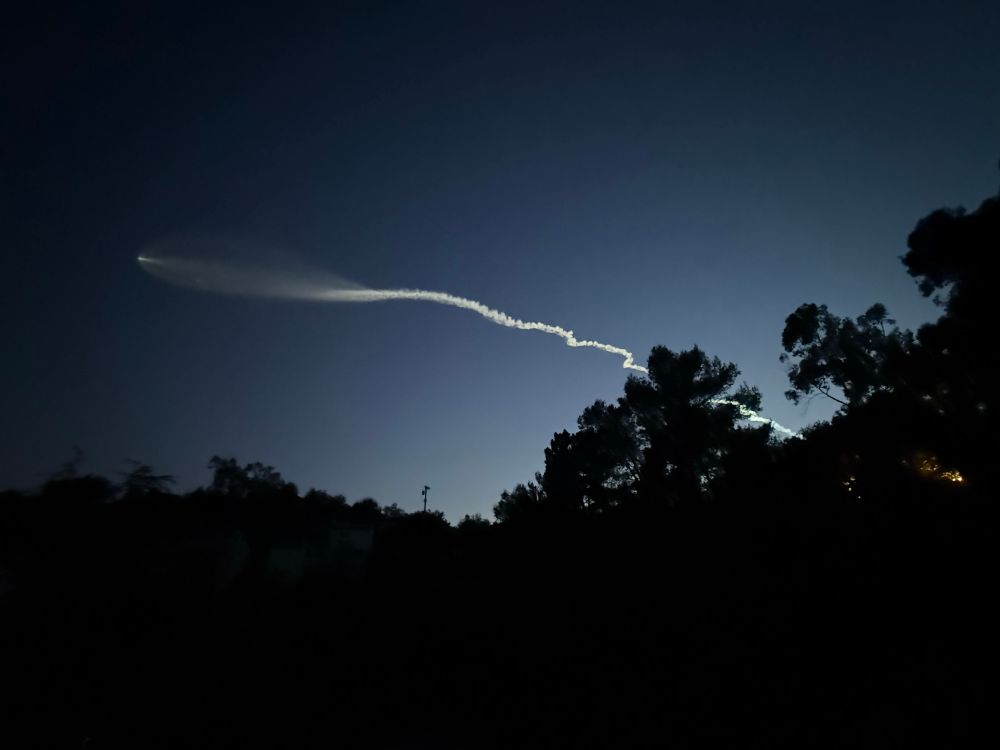 Wide angle view of the rocket and plume lit up by the setting sun
