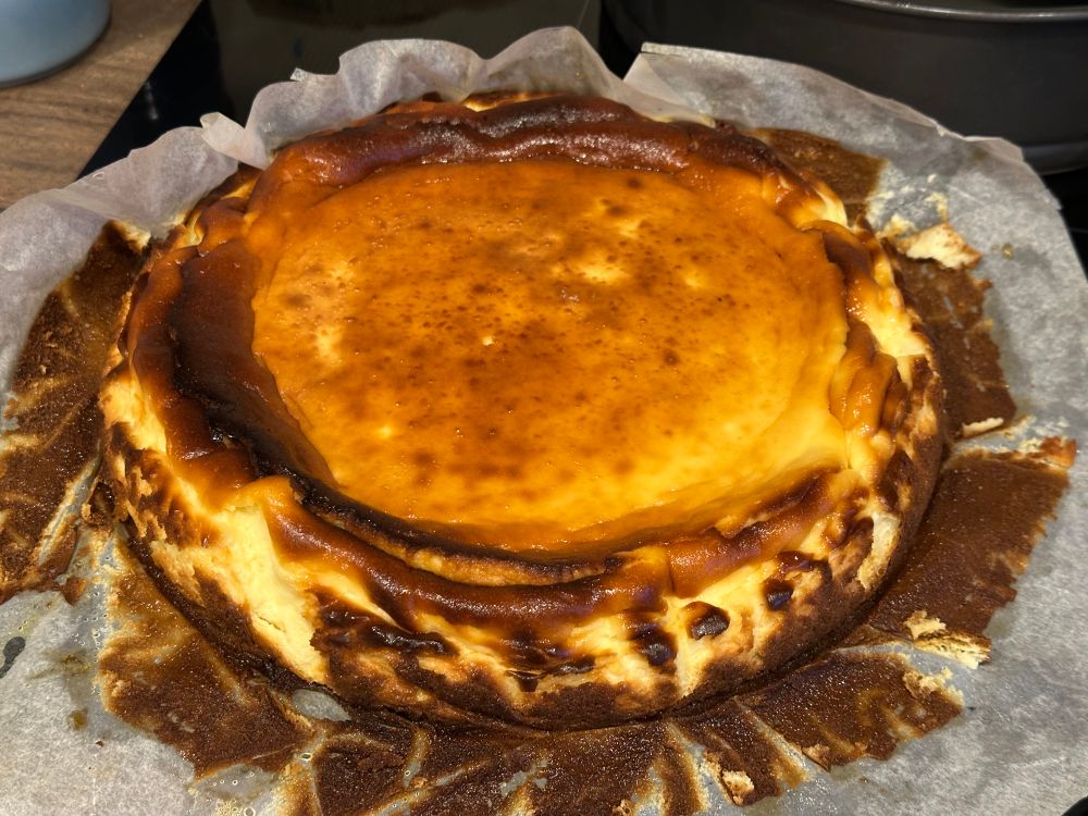 A full basque burnt cheesecake with the paper peeled off revealing the craggly edges 