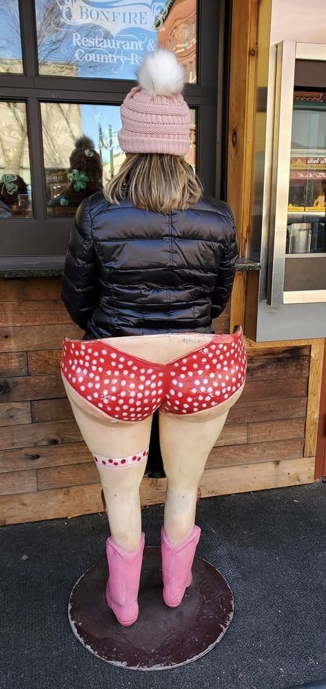 I'm wearing a black puffy jacket and pink beanie while sitting in front of a window on a stool shaped like legs in red polka-dot shorts and pink boots, making it look like they’re my lower half.