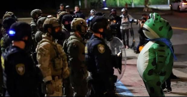 The hero Portland needed, a person in an inflatable frog costume, bravely stares down a bunch of dipshit cops 
