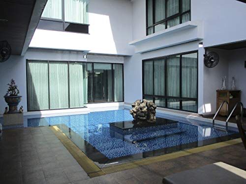 A modern mansion in Bangkok with floor to ceiling windows overlooking a glimmering courtyard wading pool with gilt statues. From there's show House Hunters International 