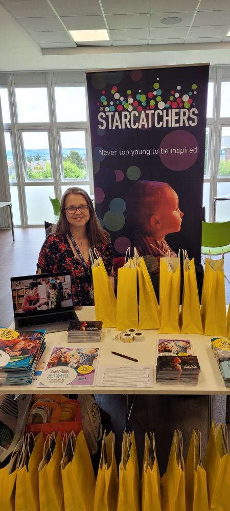 Early Years Development Manager, Sharon May, sits at a stall surrounded by resources and creativity packs