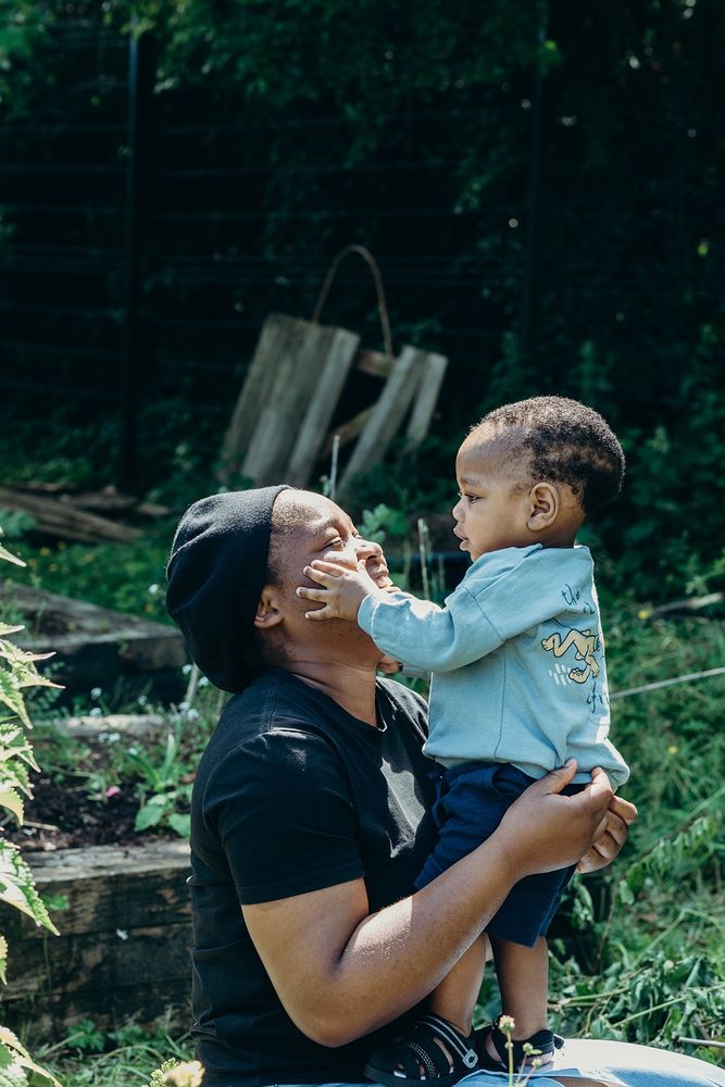 A mum smiling at her young child as he holds her face