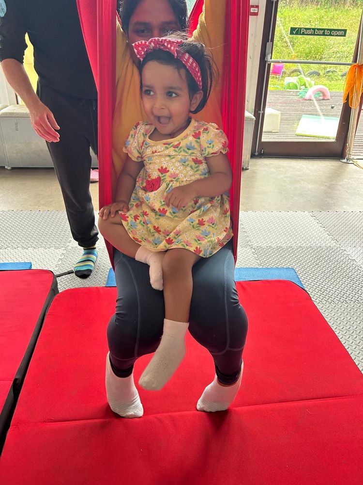 Mother and baby sat in a silk set up like a swing