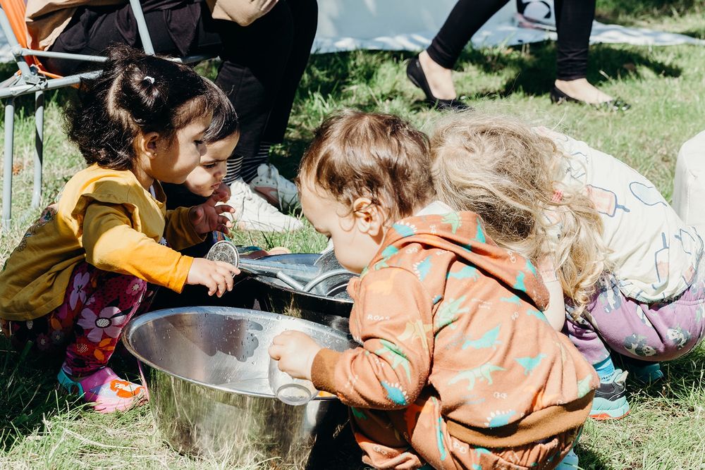 Young children all playing with water and metal bowls