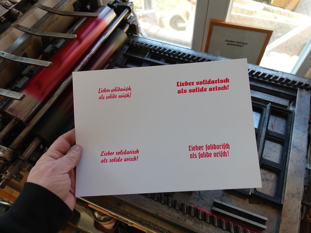 Foto meiner Hand die einen Abzug mit vier Schriftzügen gleichen Inhalts aber in verschiedenen Schriftarten zeigt. Der Text lautet: Lieber solidarisch als solide arisch!