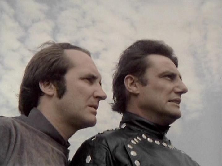 

Claude 3.7 describes the image as: "The image shows two people in profile against a cloudy sky background. The composition has them positioned side by side, both looking toward the same direction. The person on the left wears what appears to be a gray or brown outfit, while the person on the right is dressed in a distinctive black leather costume with metallic studs or embellishments along the collar.

The styling and aesthetic suggests this is from a vintage science fiction production, likely from the late 1970s or early 1980s based on the film quality and costume design. The dramatic positioning and serious expressions indicate this might be from a tense or important scene. The leather costume with its militaristic or futuristic styling is particularly notable as a characteristic element of the visual design from this era of television."

Blakes7Bot, version 3.9.31. AWS Lambda version: 1.14.