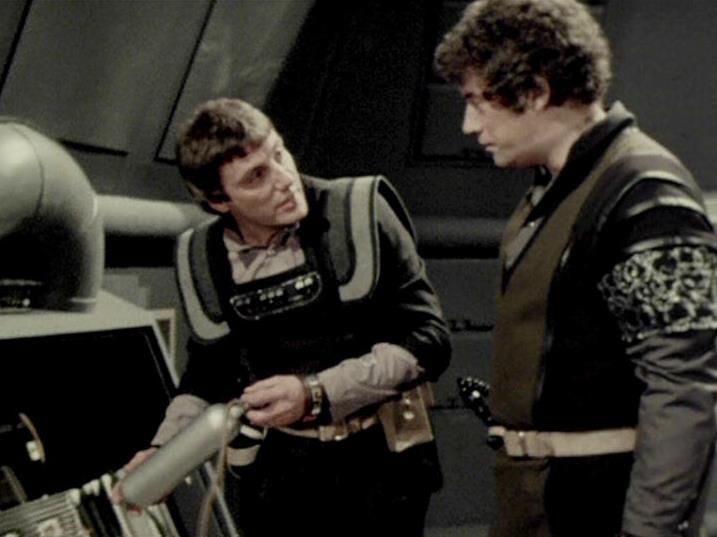 

Claude Sonnet 4.0 describes the image as: "This appears to be a scene set aboard a spacecraft, likely the Liberator, showing two crew members in a technical or engineering area. The setting features the show's characteristic futuristic interior design with metallic surfaces and technological equipment. One character is leaning over what appears to be some kind of control panel or technical apparatus, while another stands nearby observing. Both are wearing the dark, military-style clothing typical of the series. The scene suggests they are engaged in some kind of technical discussion or problem-solving activity, which was common given the crew's frequent need to maintain their ship and equipment while evading the Federation."

Blakes7Bot, version 3.9.31. AWS Lambda version: 1.14.