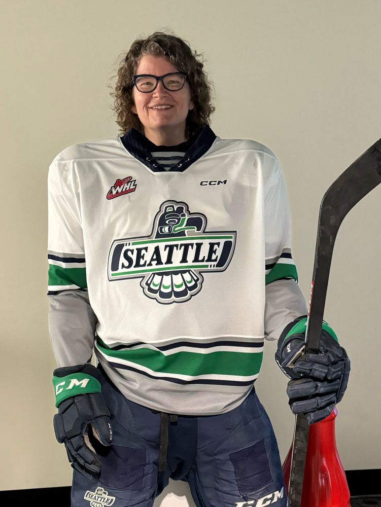Person posing behind a headless set of Seattle Thunderbirds gear with hockey stick who is clearly too old and plump to play hockey with teenagers 