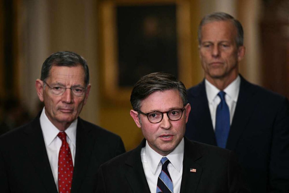 Mike Johnson at a press conference, behind him John Barrasso and John Thune, who looks contemplatively down.