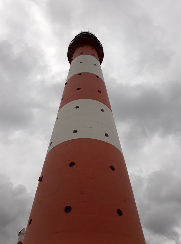 Ein Leuchtturm ragt standhaft in einen wolkigen Himmel 