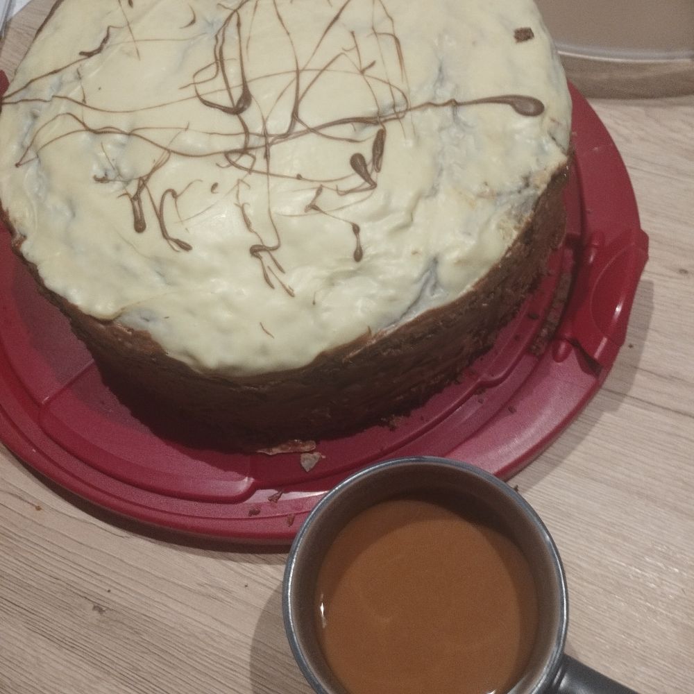 Im Bild eine Tasse Kaffee rechts unten und eine Nusstorte mit drei verschiedenen Böden aus Pistazien, Mandeln und Haselnuss mit Butterkrokant und Walnusskaramell. 