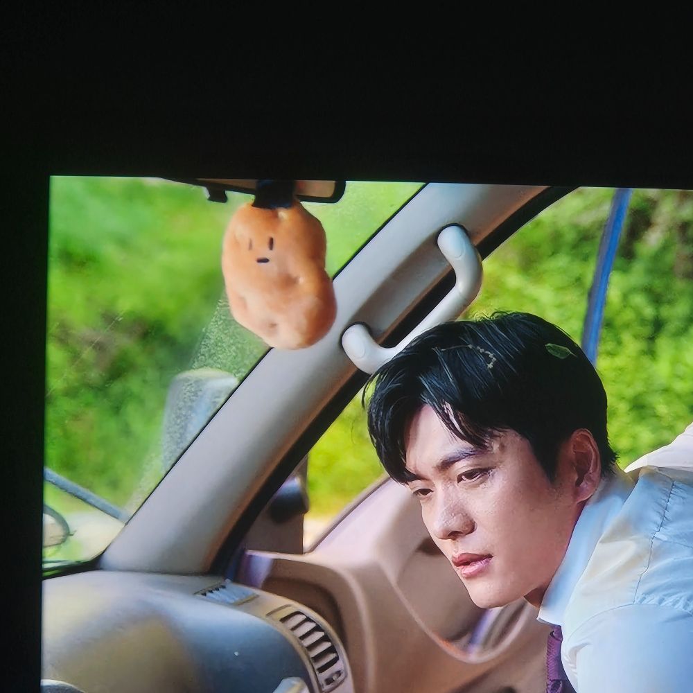 A pic from "The potato lab" K drama showing kang tae oh getting into a van and a cute potato plushie hanging from the rear view mirror 