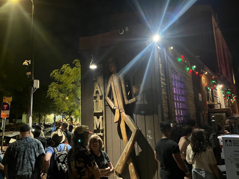 People gather in front of the Palmer’s wooden figurine