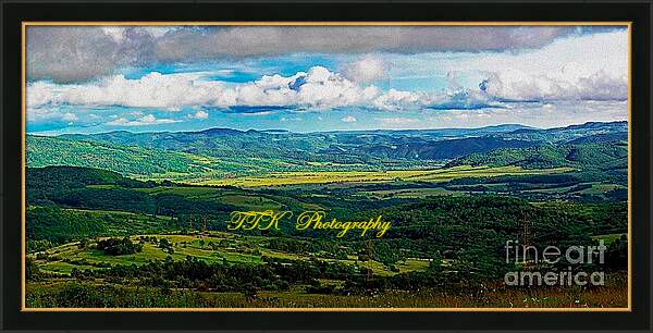 Rural panoramic view of a valley surrounded by wooded hills in mid summer.The fluffy clouds, remnants after rain create a game of shadows and light across the landscape. Digital painting with texture from a stitched panoramic photograph.Framed artprint.