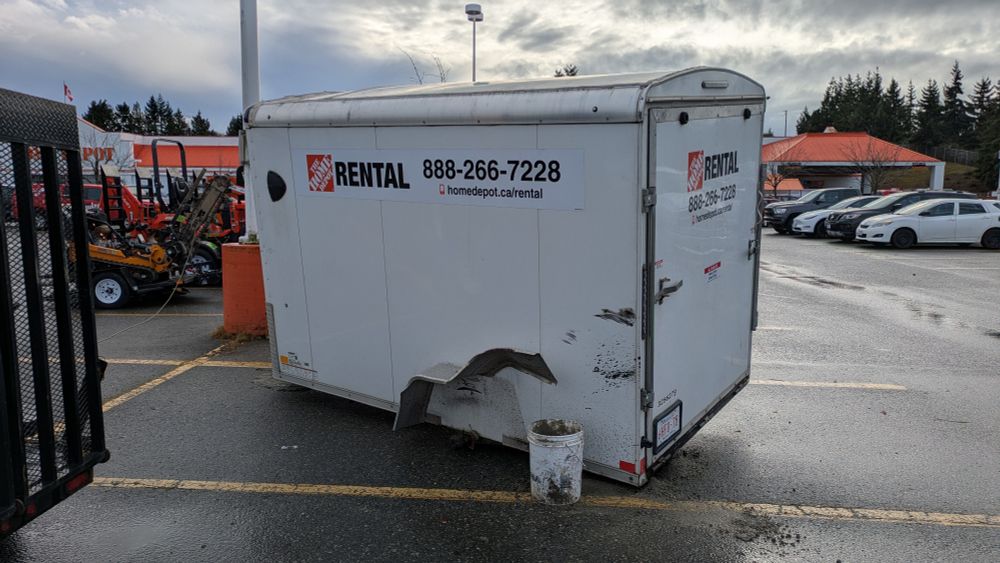 Busted up Home Depot trailer with a missing wheel.