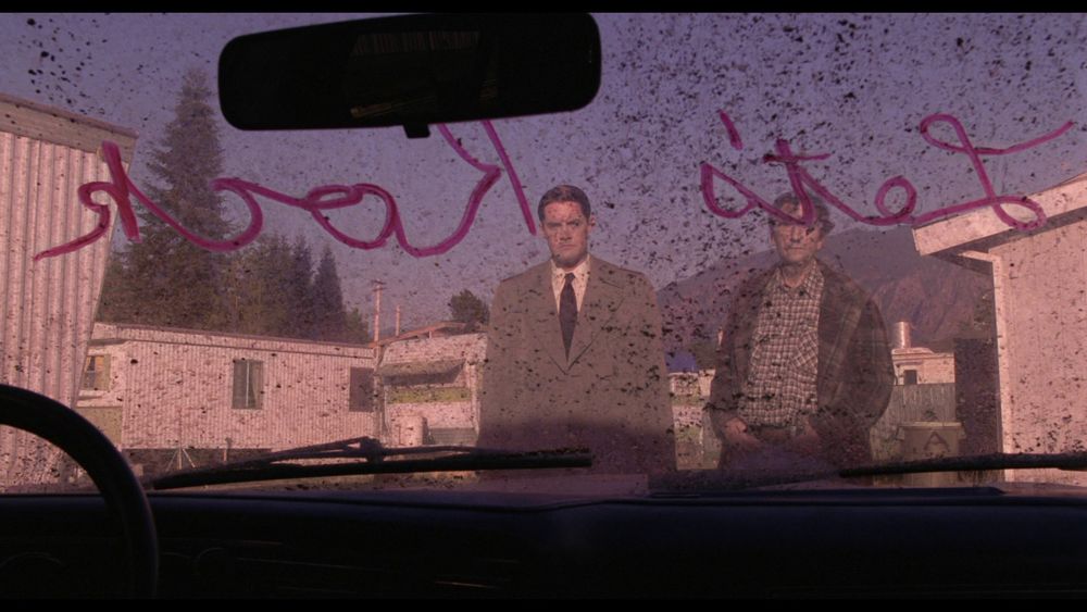 Cooper and Carl looking into a dirty car's windshield, "Let's Rock" is written in red on it