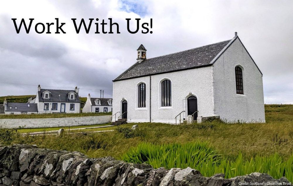 A white washed small Scottish church in a grassy field with a stone wall in front 
